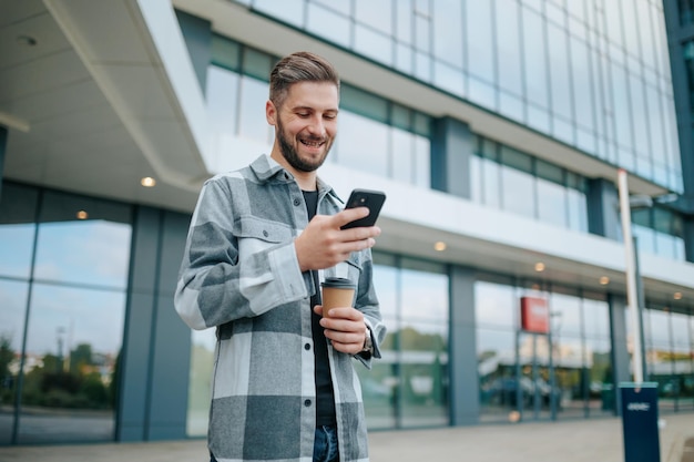 Gevangen in een stedelijke buitenomgeving vindt een glimlachende jongeman geluk via zijn smartphones