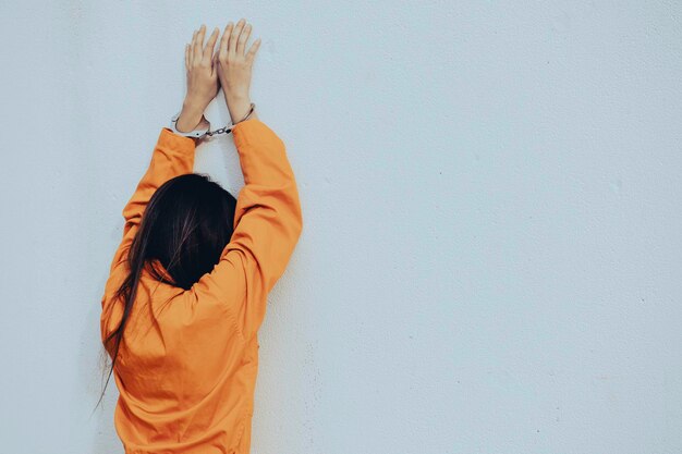 Gevangene in oranje gewaad conceptportret van Aziatische vrouw in gevangenisuniformen op witte achtergrond