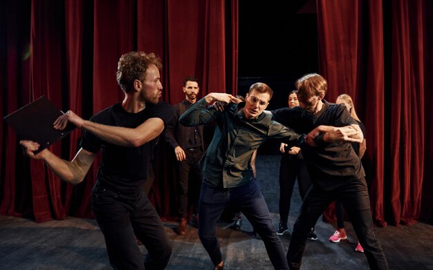 Gevechtsscene Groep acteurs in donkere kleren op een repetitie in het theater