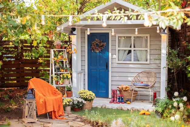 Gevel herfst Gezellige woning met veranda met stoel, deken, chrysanten.