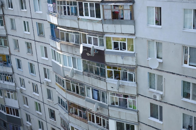 Gevel van een grijze sovjet-paneelbouw met meerdere verdiepingen russische oude stedelijke woonhuizen met ramen en balkon russische buurt