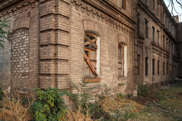 Gevel van oud verlaten bakstenen gebouw met raam bekleed met houten planken
