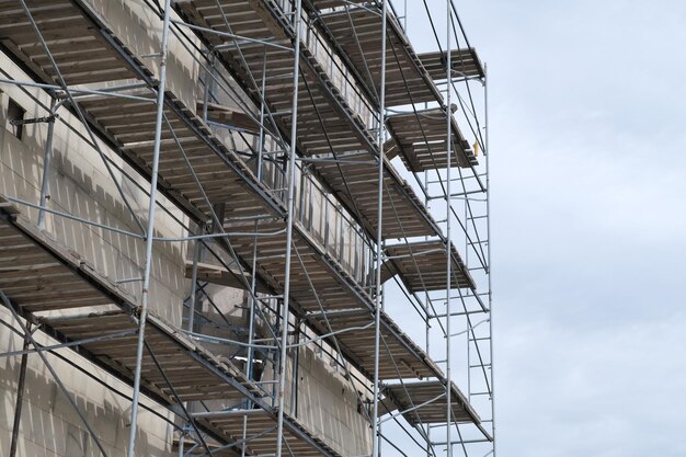 Gevelrestauratie van gebouw tegen bewolkte hemel Wederopbouw van buitenkant van gebouw met steigers