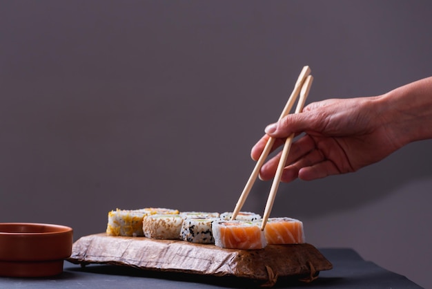 Gevoelige handen met eetstokjes die sushi uit een dienblad trekken