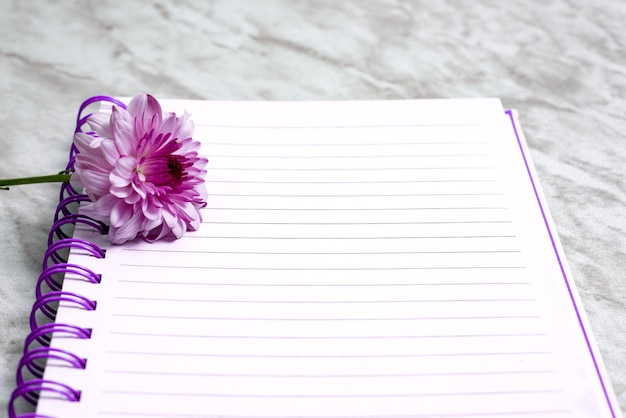 Gevoerd notitieboekje met bloemen eromheen op marmeren tafel