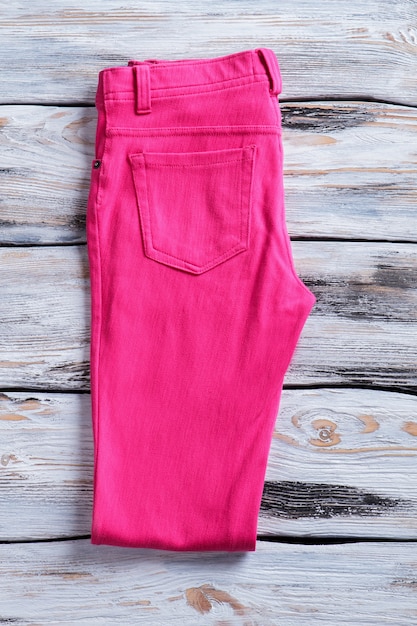 Gevouwen broek van roze kleur. broek op witte houten achtergrond. gloednieuwe broek voor dames. stijlvol en kleurrijk.