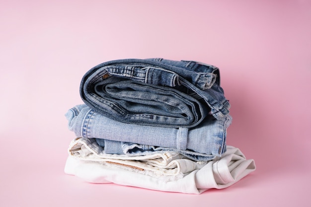 Gevouwen geassorteerde jeans op een roze achtergrond.