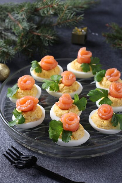 Gevulde eieren met gezouten zalm en kaas, een heerlijke feestelijke snack op een donkere achtergrond.