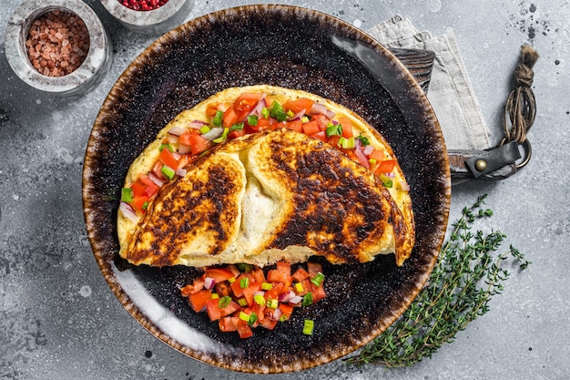 Gevulde eiomelet met tomatenui en kruiden op een bord Grijze achtergrond Bovenaanzicht