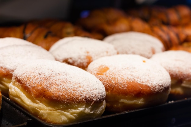 Gevulde geglazuurde donuts en chocoladecroissants op de etalage van de bakkerij. Zoet dessertconcept