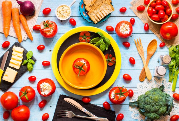 Gevulde tomaten met kaas en verschillende groenten, op een houten tafel,