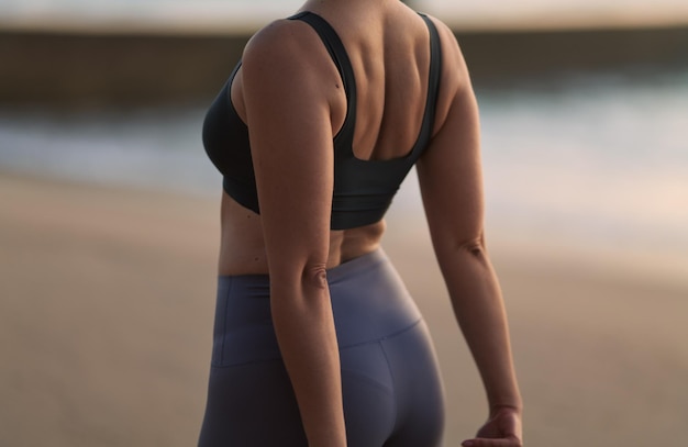 Gewas anonieme sportvrouw die zich uitstrekt terug op zandige kust