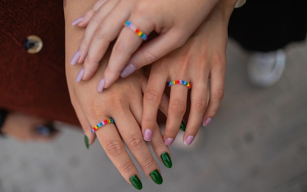 Gewas van drie meisjes die haar stijlvolle manicure tonen die hun vingers op zwart lederen handtas houden Ander ontwerp van manicure na schoonheidssalon Vrouwelijke handen met ringen Concept van schoonheid