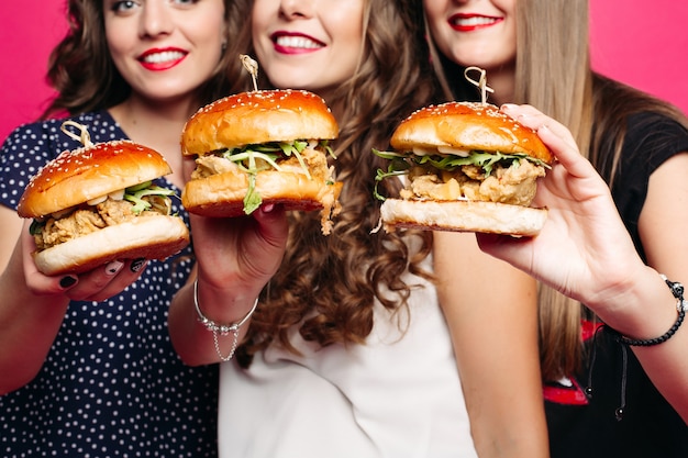 Gewas van vrienden die lekkere hamburgers met kip en groenten houden.