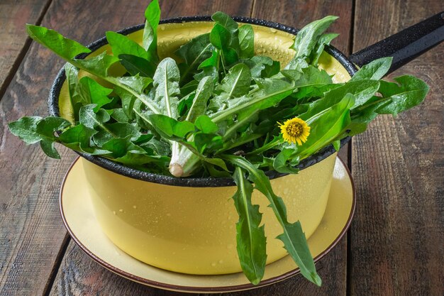 Gewassen paardebloembladeren in een vergiet, voorbereid voor lente-vitaminesalade op een houten tafel