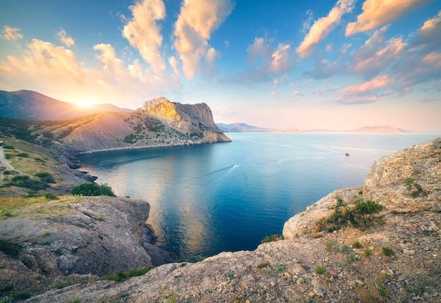 Geweldig berglandschap bij zonsondergang. Mooie scène met bergen, blauwe zee, hoge rotsen, strand, bos en kleurrijke blauwe lucht met wolken in de zomer. Reizen in Europa. Zeegezicht. Natuur achtergrond