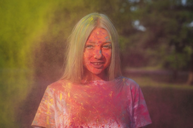 Geweldig blond model dat speelt met exploderend geel droog poeder op het Holi-festival