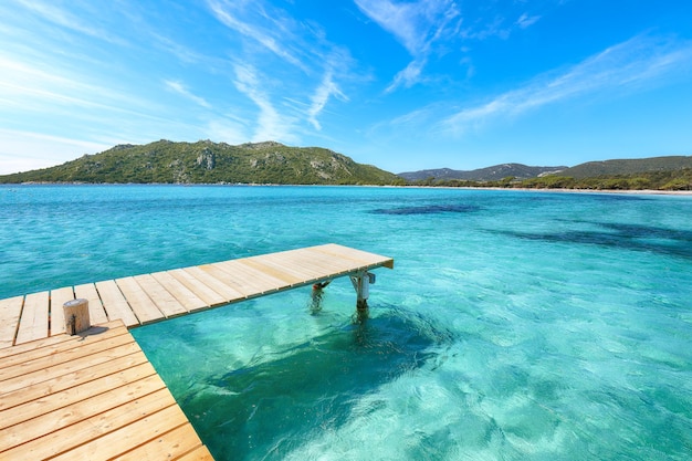 Geweldig landschap met houten pier op het strand van Santa Giulia