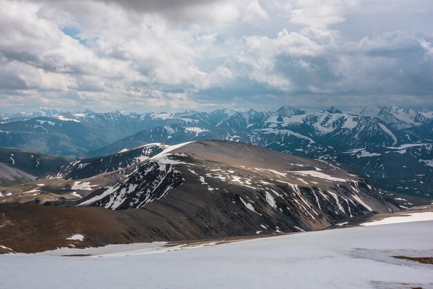 Geweldig luchtfoto om bergen te besneeuwen onder bewolkte hemel Schilderachtig berglandschap op zeer grote hoogte met bewolking Atmosferisch berglandschap met prachtige besneeuwde bergketen in bewolking