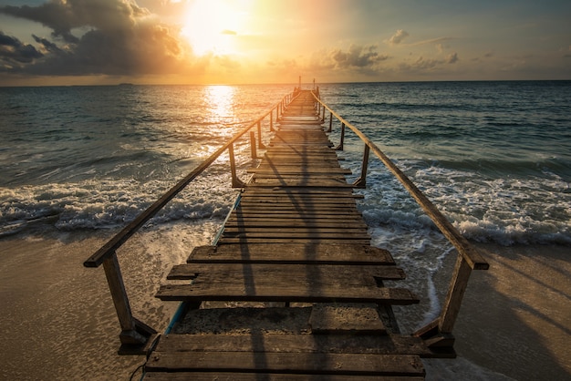 Geweldig tropisch zandstrand met silhouet houten brug uit het strand tropisch - Boardwalk of houten loopbrug naar de horizon op zee oceaan paradijs landschap, zonsopgang of zonsondergang zee dramatische hemel