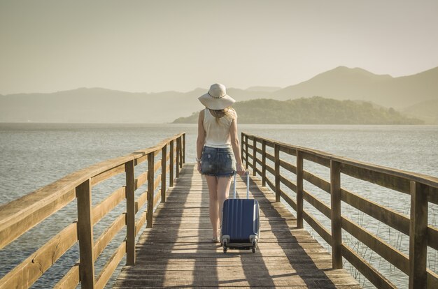 Geweldig vakantieconcept. Jonge vrouw met haar koffer, wachtend op de boot op de kade