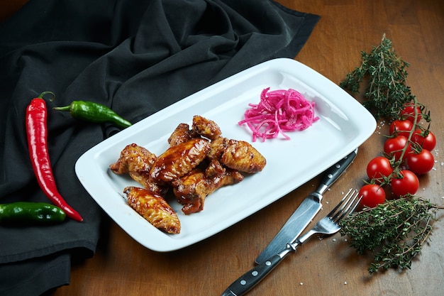 Geweldige biersnack - pittig gebakken buffelvleugels. BBQ-vleugels met garnituur van salade op witte plaat. Detailopname. Pub eten