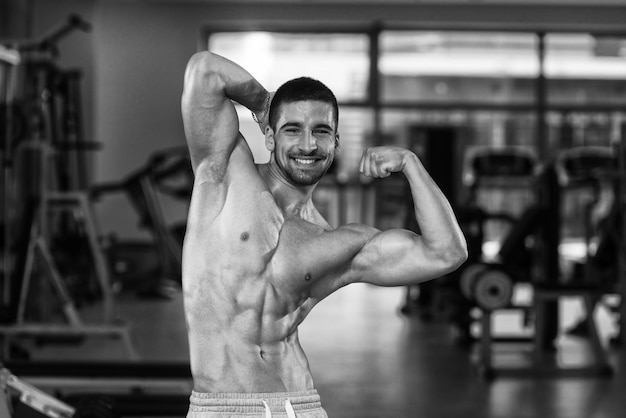 Geweldige bodybuilder die zijn spieren laat zien en in de sportschool poseert