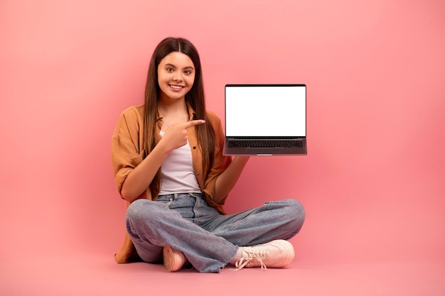Geweldige website vrolijk tienermeisje wijst naar laptop met leeg scherm