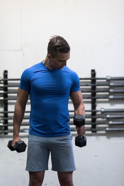 gewicht opleiding fitness man binnen het uitwerken van armen tillen halters doen biceps krullen. Mannelijk sportmodel dat binnenshuis traint als onderdeel van een gezonde levensstijl.