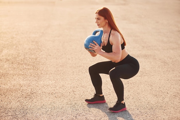 Gewichtheffen Vrouw in sportkleding heeft 's avonds een fitnessdag op de weg