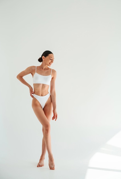 Gewichtsverlies conceptie Vrouw in witte ondergoed met slank lichaam tegen witte achtergrond