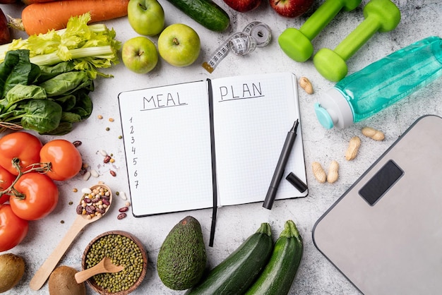 Foto gewichtsverlies en dieet concept notepad met woorden maaltijdplan met gezonde voedingsmiddelen en sportapparatuur