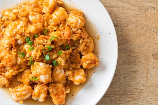 Gewokte garnalen met knoflook en garnalenpasta op wit bord