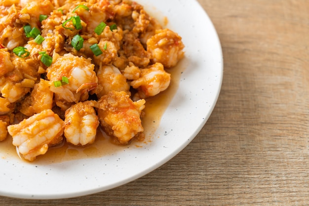 Gewokte garnalen met knoflook en garnalenpasta op wit bord