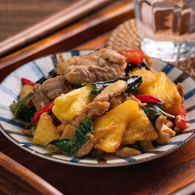 Gewokte Taiwanese Three Cup Chicken met ananas. Zelfgemaakt heerlijk eten in Taiwan op donker houten tafelblad.