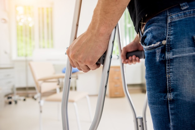 Gewonde man probeert te lopen op krukken in het ziekenhuis.