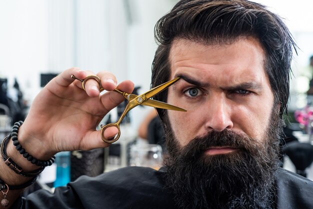 Gewoon fantastisch haar. kapper meester knippen haar met een schaar. volwassen hipster met baard bij kapper. brutale hipster met snor maakt nieuw kapsel. kapperszaak. mannelijk trendy kapsel. perfecte kapsel.