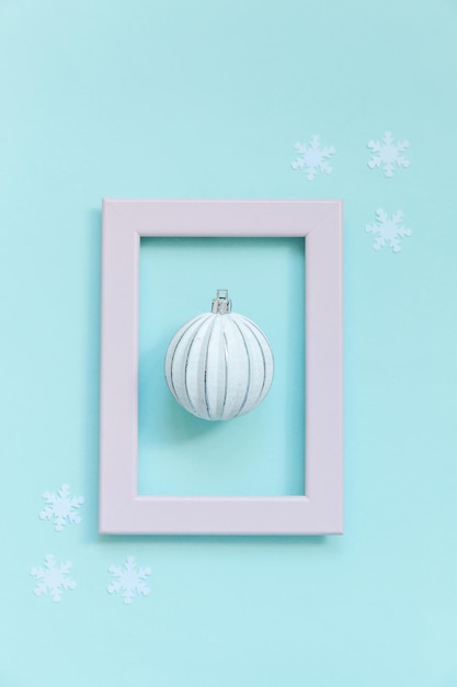 Gewoon minimale samenstelling winter objecten ornament bal in roze frame geïsoleerd op blauwe pastel trendy achtergrond. Kerstmis Nieuwjaar december tijd voor viering concept. Platliggend bovenaanzicht