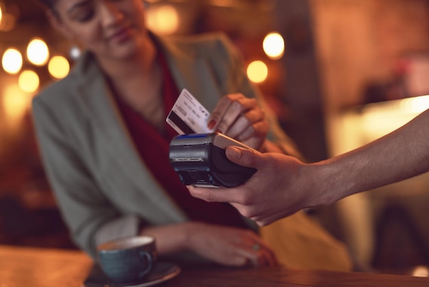 Gewoon vegen close-up shot van een jonge vrouw die haar creditcard doorhaalt om een betaling te doen in een café