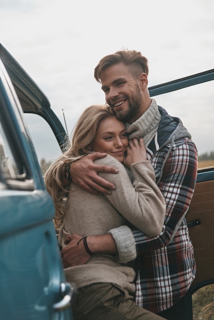 Gewoon verliefd. Mooie jonge paar omhelzen en glimlachen terwijl ze buiten staan in de buurt van de retro-stijl minibus