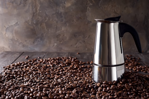 Macchinetta del caffè del geyser sui precedenti dei chicchi di caffè su un fondo di legno scuro, spazio della copia