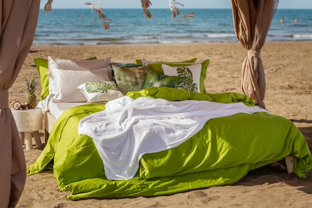 Gezellig bed op een strand in groen beddengoed