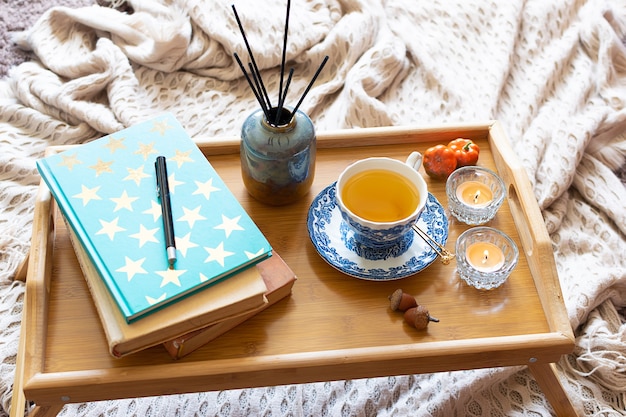 Foto gezellig interieur met kopje kruidenthee, aromatische kaarsen, warme deken en boeken.