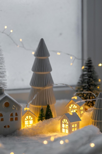 Gezellig kerstminiatuurdorpje Stijlvolle keramische huisjes en houten bomen op zachte sneeuwdeken met gloeiende lichten in de avond Sfeervol winterdorp stilleven Vrolijk kerstfeest