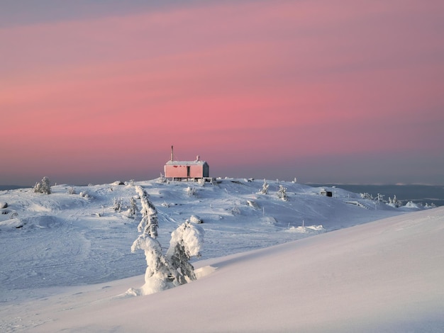 Gezellig noordelijk pension op een besneeuwde heuvel bij zonsopgang Hut in de winter bij zonsopgang Eenzaam huis op een heuveltop in de koele ochtend