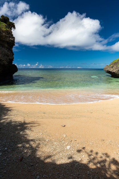 Gezellig strand, smaragdgroene zee, blauwe lucht, witte wolken, kustrotsen. Iriomote eiland.