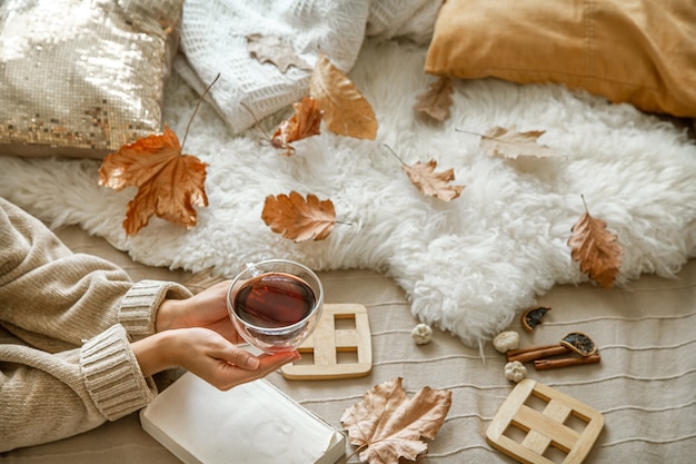 Gezellige herfst in huis, een vrouw met een boek en thee rusten. gezellige manier van leven.