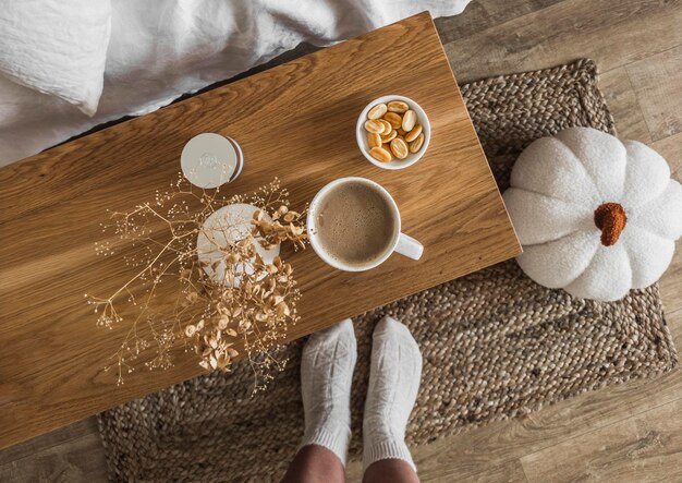 Gezellige herfstochtend damesvoeten in warme sokken een kopje koffiekoekjes op een houten bankje bij het bed