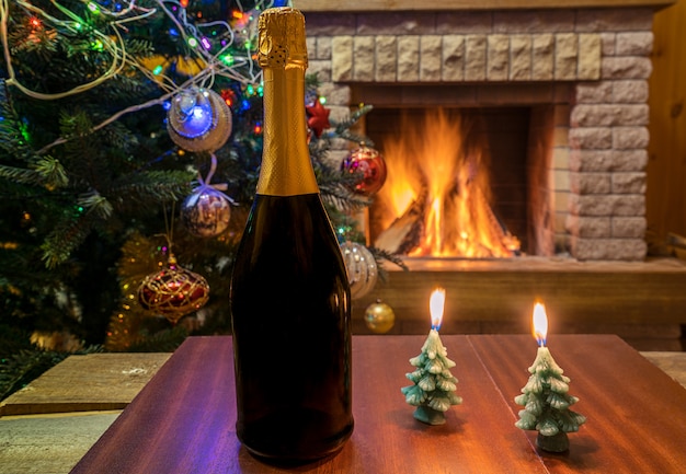 Gezellige open haard. Champagne wijn en kaarsen voor kerstboom versierd speelgoed en kerstverlichting.