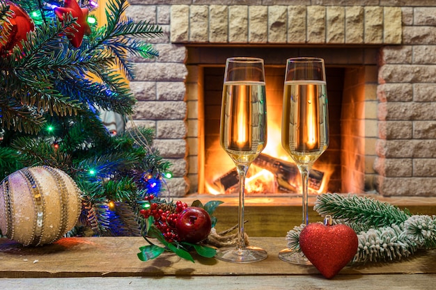 Gezellige open haard. Champagne-wijn vóór kerstboom verfraaid speelgoed en Kerstmislichten in plattelandshuisje.
